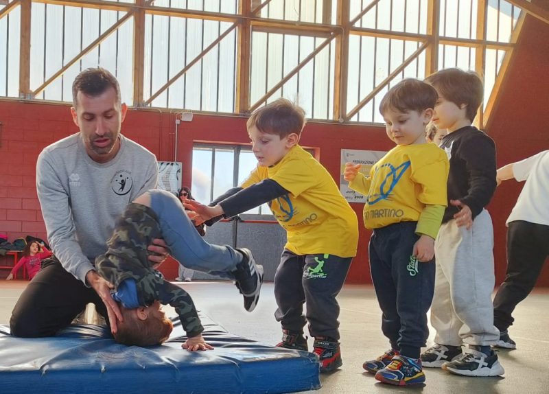 Bambino che prova una capriola assistita durante il corso di motricita
